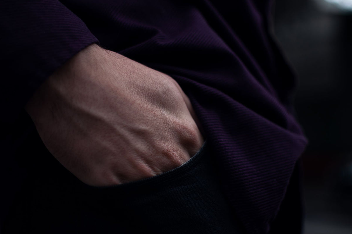 Moody shot of a person's hand in a pocket, highlighting texture and shadows.