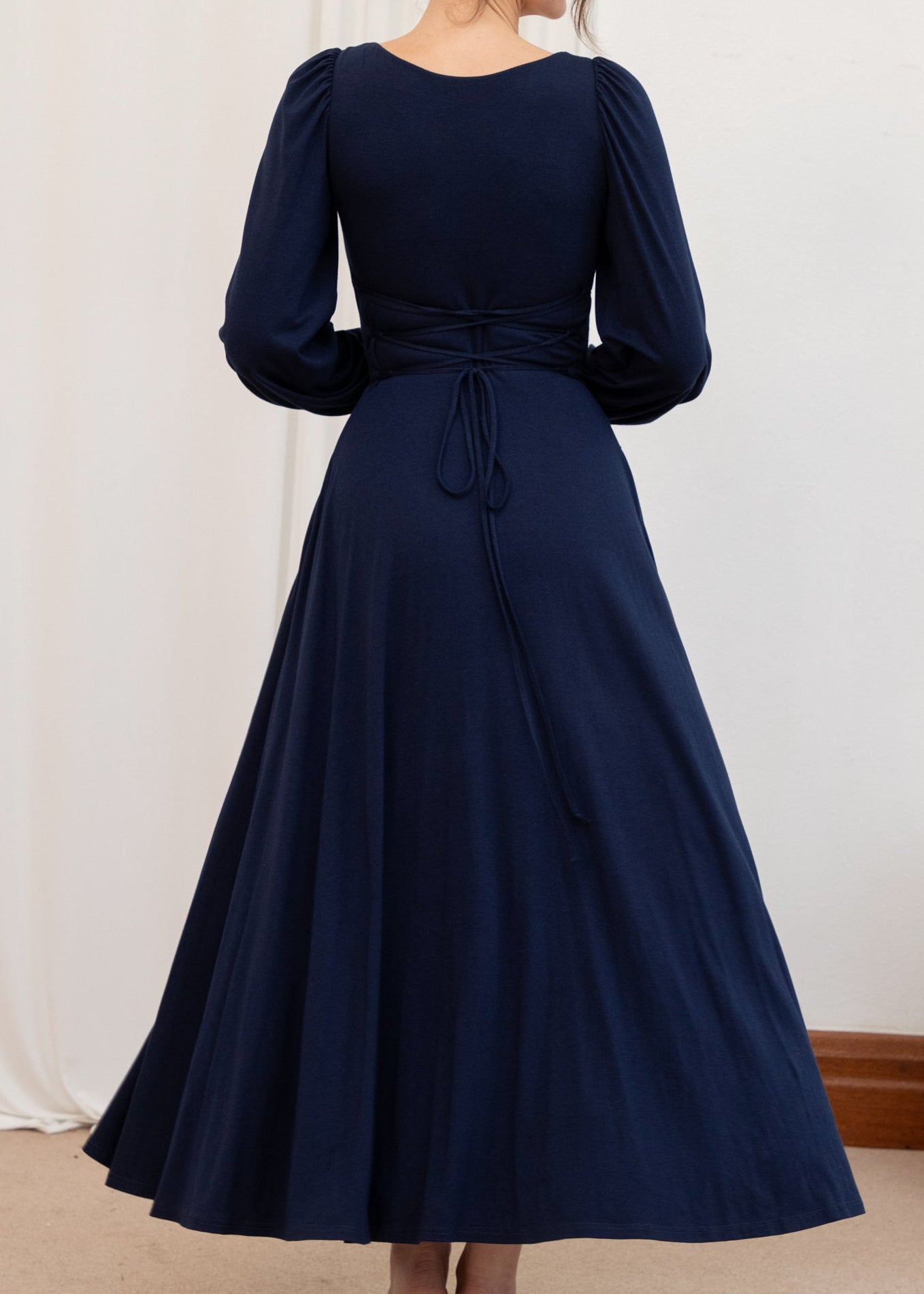 Navy blue dress with long sleeves and a tie waist on a plain background